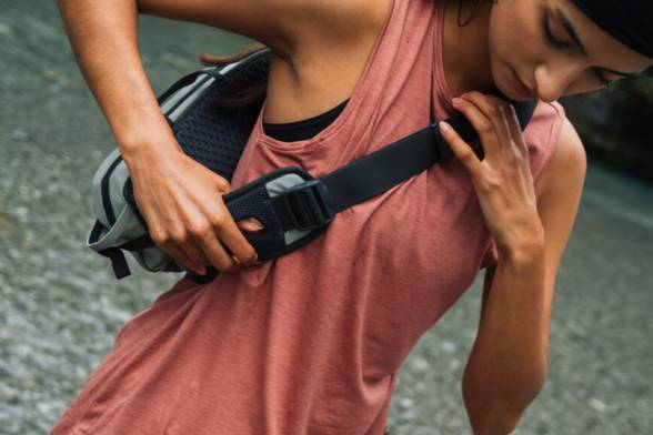 Jeune femme en tenue de randonnée estivale sportive avec sac à bandoulière sportif